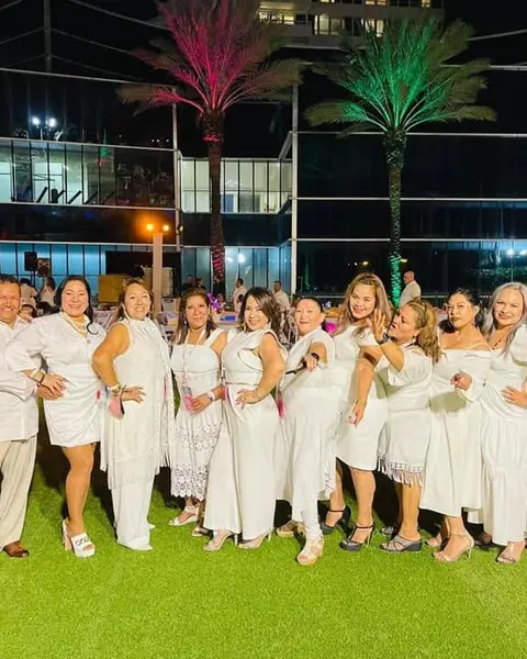Carina con un grupo grande de consultores vestidos de blanco, de noche